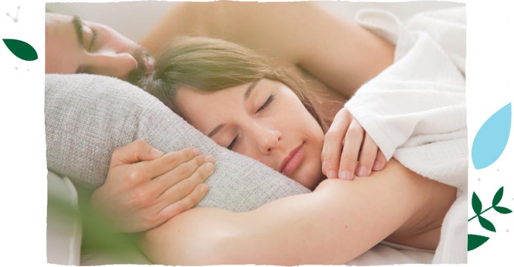 Man and woman lying calmly in bed and holding each other in sleep.